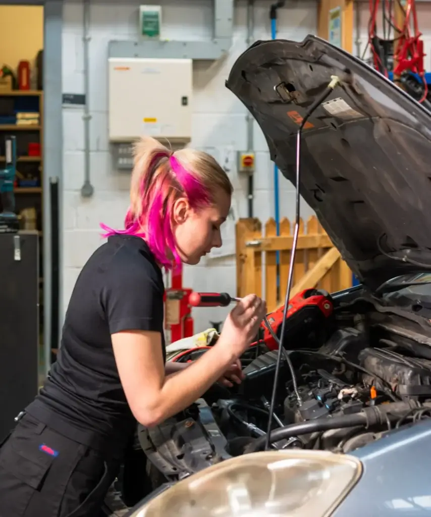 a female Motor Vehicle student working on an engine under the bonnet