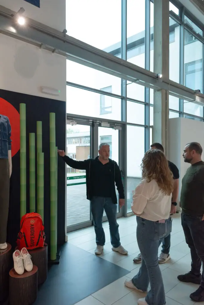Male speaking to a group of people, pointing to a window display