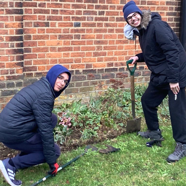 Students volunteering in a church garden working on a flower bed